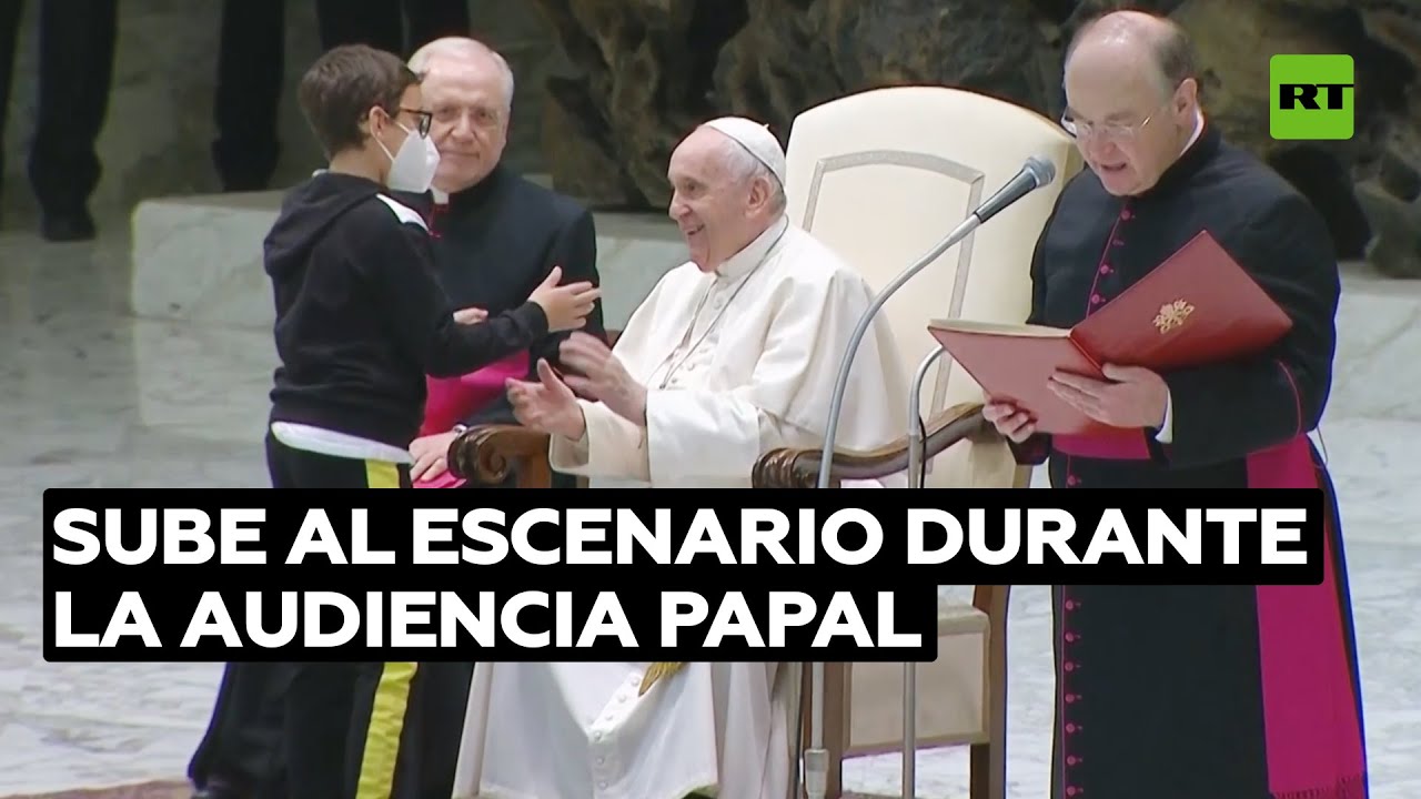Un niño sube al escenario y consigue sentarse junto a Francisco y una gorra papal de regalo
