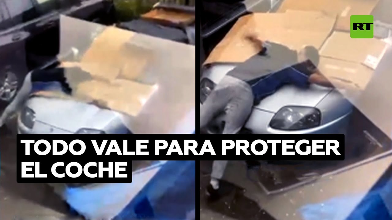 Un hombre protege su coche deportivo del granizo con el cuerpo @RT Play en Español