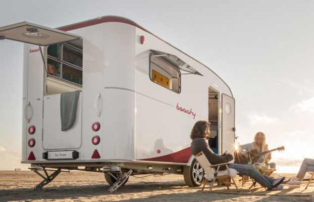 El remolque para acampar con curvas y surfistas es una barraca transformadora frente al mar