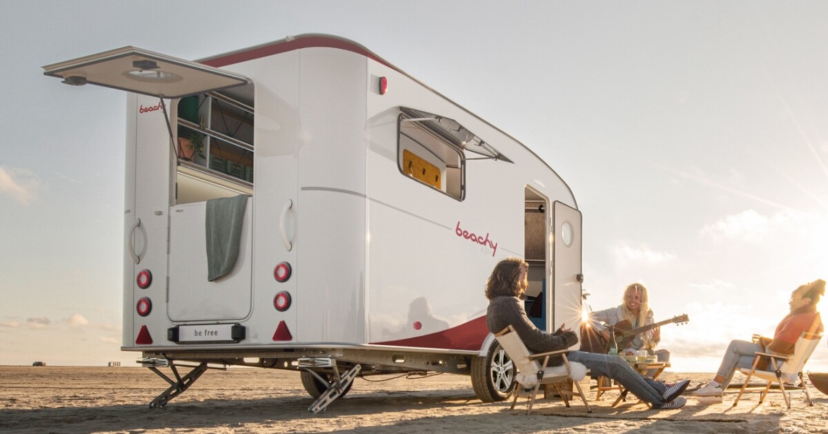 El remolque para acampar con curvas y surfistas es una barraca transformadora frente al mar